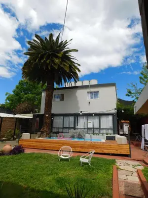 a house with a palm tree and a bench at Hotel Posada Del Lago in Villa Carlos Paz