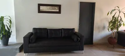 a black leather couch in a living room with a plant at Hotel Posada Del Lago in Villa Carlos Paz