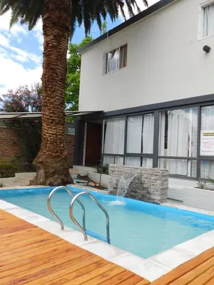 a swimming pool in front of a house at Hotel Posada Del Lago in Villa Carlos Paz
