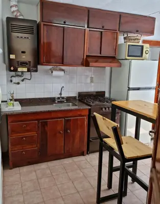 a kitchen with wooden cabinets and a sink and a table at Dto Marian Dean funes 2515 Alto Alberdi in Cordoba
