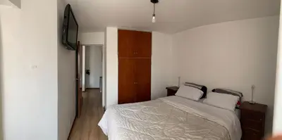 a bedroom with a white bed and a wooden cabinet at Salguero Residential Apartament in Cordoba