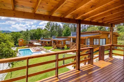a large deck with a house and a pool at Monviso - Casas de montaña in Santa Rosa de Calamuchita