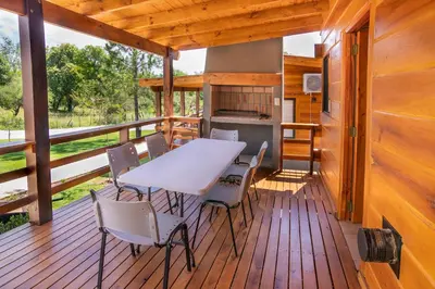 a table and chairs on the deck of a cabin at Monviso - Casas de montaña in Santa Rosa de Calamuchita
