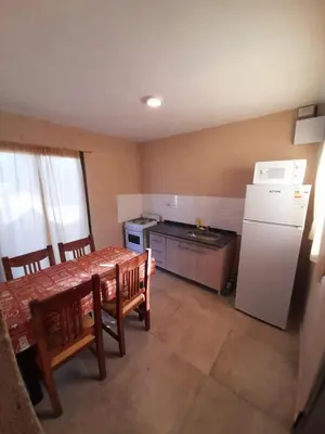 a kitchen with a table and a white refrigerator at SIMION in Villa Carlos Paz