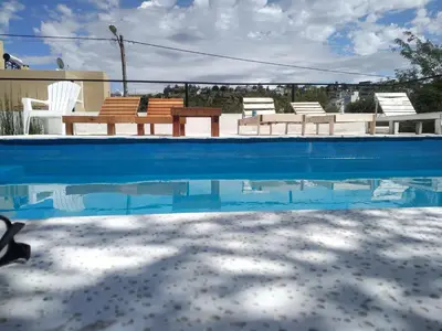 a swimming pool with chairs and a table and water at SIMION in Villa Carlos Paz
