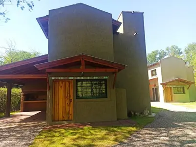 a house with a wooden door in the grass at Papa Ruku in Villa Ciudad Parque