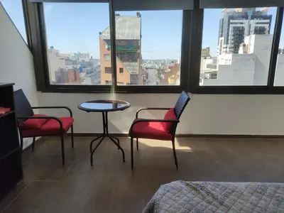 a room with two chairs and a table and windows at Piso Completo en Nueva Córdoba in Cordoba