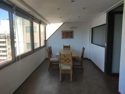 a dining room with a table and chairs and windows at Piso Completo en Nueva Córdoba in Cordoba
