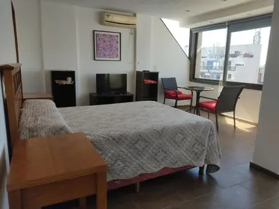 a bedroom with a bed and chairs and a television at Piso Completo en Nueva Córdoba in Cordoba