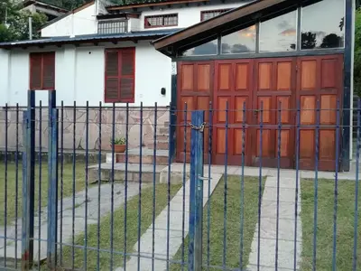 a fence in front of a house with red doors at Carlos Paz Colinas House in Villa Carlos Paz
