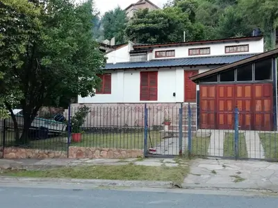 a white house with red doors and a fence at Carlos Paz Colinas House in Villa Carlos Paz