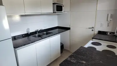 a small white kitchen with a sink and a microwave at Torre del Lago V in Villa Carlos Paz