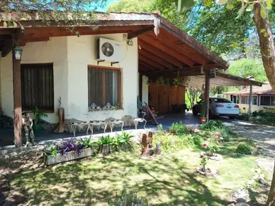 a house with a patio and a yard with flowers at Casa del arroyo in Villa General Belgrano