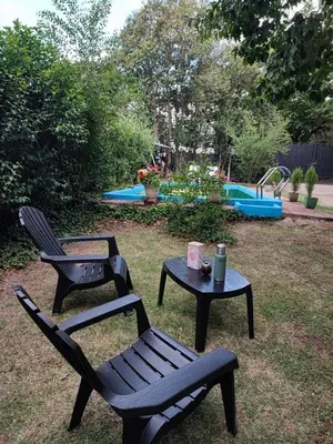 two chairs and a table in a yard with a pool at Casa del arroyo in Villa General Belgrano