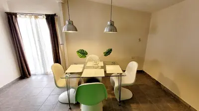 a dining room with a table and a green chair at Victorino House en el Cerro de las Rosas con cochera in Cordoba