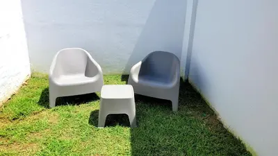 two chairs and a stool sitting next to a wall at Victorino House en el Cerro de las Rosas con cochera in Cordoba
