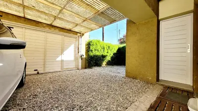 a garage with two doors and a gravel driveway at Victorino House en el Cerro de las Rosas con cochera in Cordoba