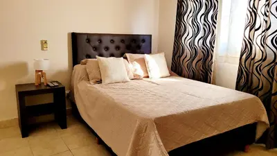 a bedroom with a bed with a black headboard and a table at Victorino House en el Cerro de las Rosas con cochera in Cordoba