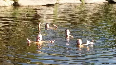 a group of people swimming in the water at Cabañas La Rustica 6p in Bialet Massé