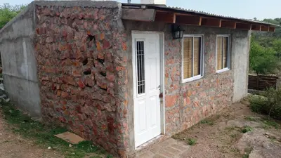a brick building with a white door on it at Cabañas La Rustica 6p in Bialet Massé