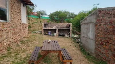 a wooden bench sitting in the grass next to a building at Cabañas La Rustica 6p in Bialet Massé