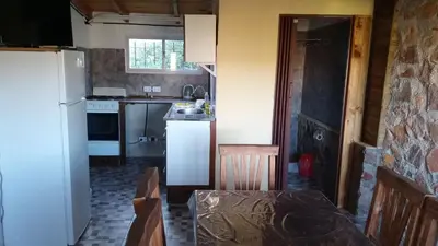 a small kitchen with a white refrigerator and a table at Cabañas La Rustica 6p in Bialet Massé