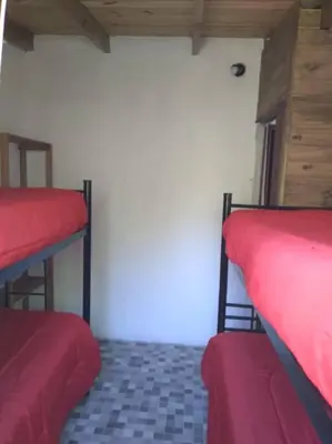 a room with two bunk beds with red sheets at Cabañas La Rustica 6p in Bialet Massé