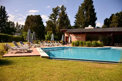 a pool with chairs and umbrellas in a yard at La Rosa Apart Hotel - Solo Parejas in Mina Clavero