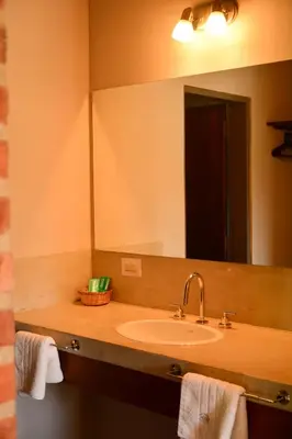 a bathroom with a sink and a large mirror at La Rosa Apart Hotel - Solo Parejas in Mina Clavero