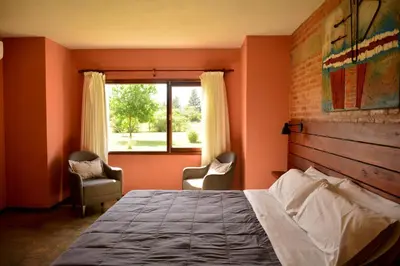 a bedroom with a bed and two chairs and a window at La Rosa Apart Hotel - Solo Parejas in Mina Clavero