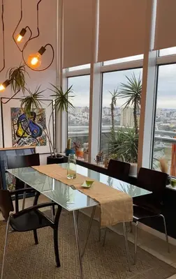 a dining room with a table and chairs and windows at DEPARTAMENTO VIP PREMIUM EN EL CENTRO - Arte y Vistas panorámicas a toda la ciudad y el río in Cordoba