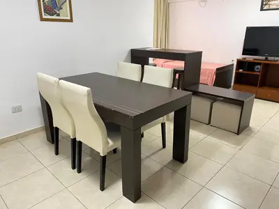 a black dining room table with white chairs and a television at Departamento Sorrentos in Villa Carlos Paz