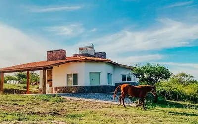 a horse standing in front of a house at CABAÑA MAR - FINCA PUDUAM in Villa General Belgrano