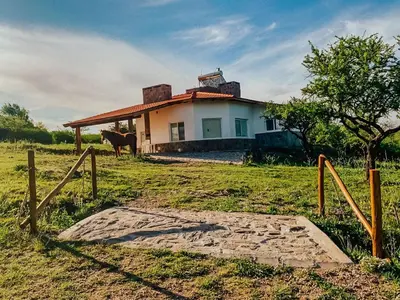 a house in a field with a horse in front of it at CABAÑA MAR - FINCA PUDUAM in Villa General Belgrano