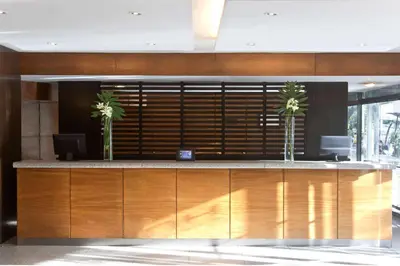 a lobby with a reception desk with two palm trees at NH Córdoba Panorama in Cordoba