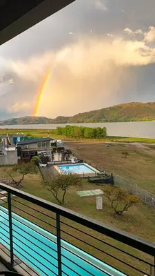 a rainbow in the sky over a pool with a house at Dpto The View, Puerto del Águila Lago Los Molinos in Potrero de Garay