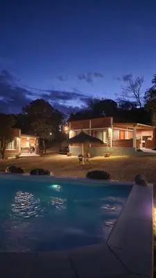 a swimming pool in front of a house at night at Los Molles Suites -Solo 2 Pax- in Mina Clavero