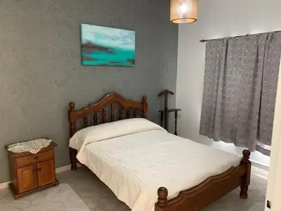 a bedroom with a bed and a table and a window at Cabaña Siete Colores II in Santa Rosa de Calamuchita