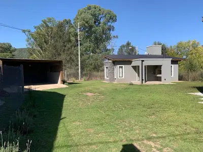 a house with a large yard in front of it at Cabaña Siete Colores II in Santa Rosa de Calamuchita