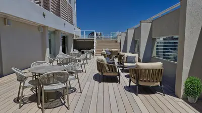 a wooden deck with tables and chairs on a balcony at Amérian Córdoba in Cordoba