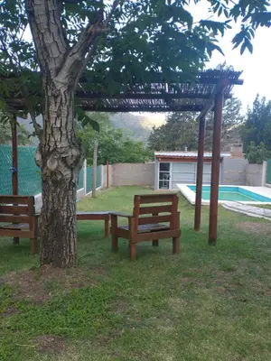 two benches sitting under a tree next to a pool at Casa Tio Molina in Bialet Massé