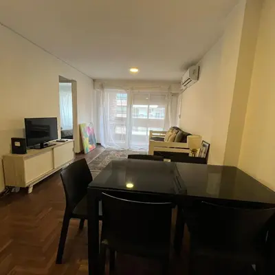 a living room with a table and chairs and a television at Pueyrredon 40, Nueva Cordoba in Cordoba