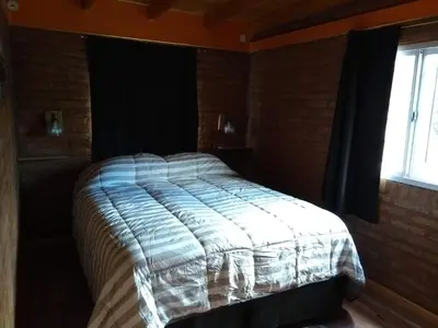 a bed in a room with a window at APART CABAÑAs LOS COCKERS in Santa Rosa de Calamuchita