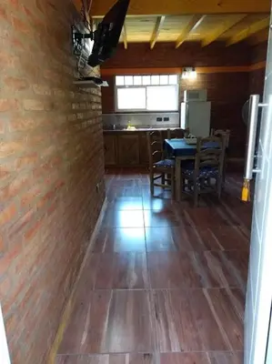 a kitchen with a wooden floor and a table with chairs at APART CABAÑAs LOS COCKERS in Santa Rosa de Calamuchita