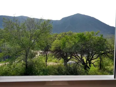 a window with a view of trees and mountains at APART CABAÑAs LOS COCKERS in Santa Rosa de Calamuchita
