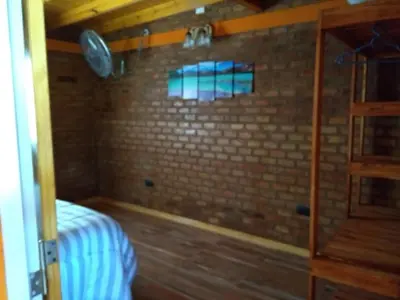a small bedroom with a brick wall and a bed at APART CABAÑAs LOS COCKERS in Santa Rosa de Calamuchita