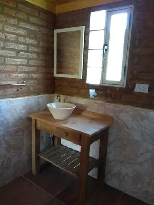 a bathroom with a bowl sink on a wooden table at APART CABAÑAs LOS COCKERS in Santa Rosa de Calamuchita