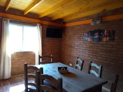 a dining room with a wooden table and chairs at APART CABAÑAs LOS COCKERS in Santa Rosa de Calamuchita