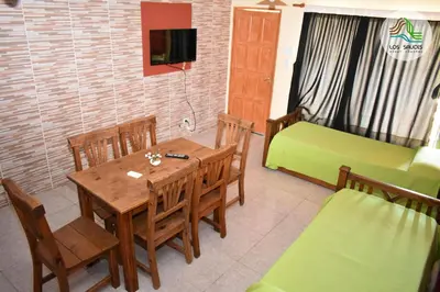 a dining room with a table and a green couch at APART CABAÑAS LOS SAUCES in Tanti