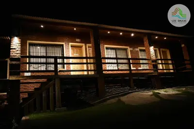 a house with a wooden deck at night at APART CABAÑAS LOS SAUCES in Tanti